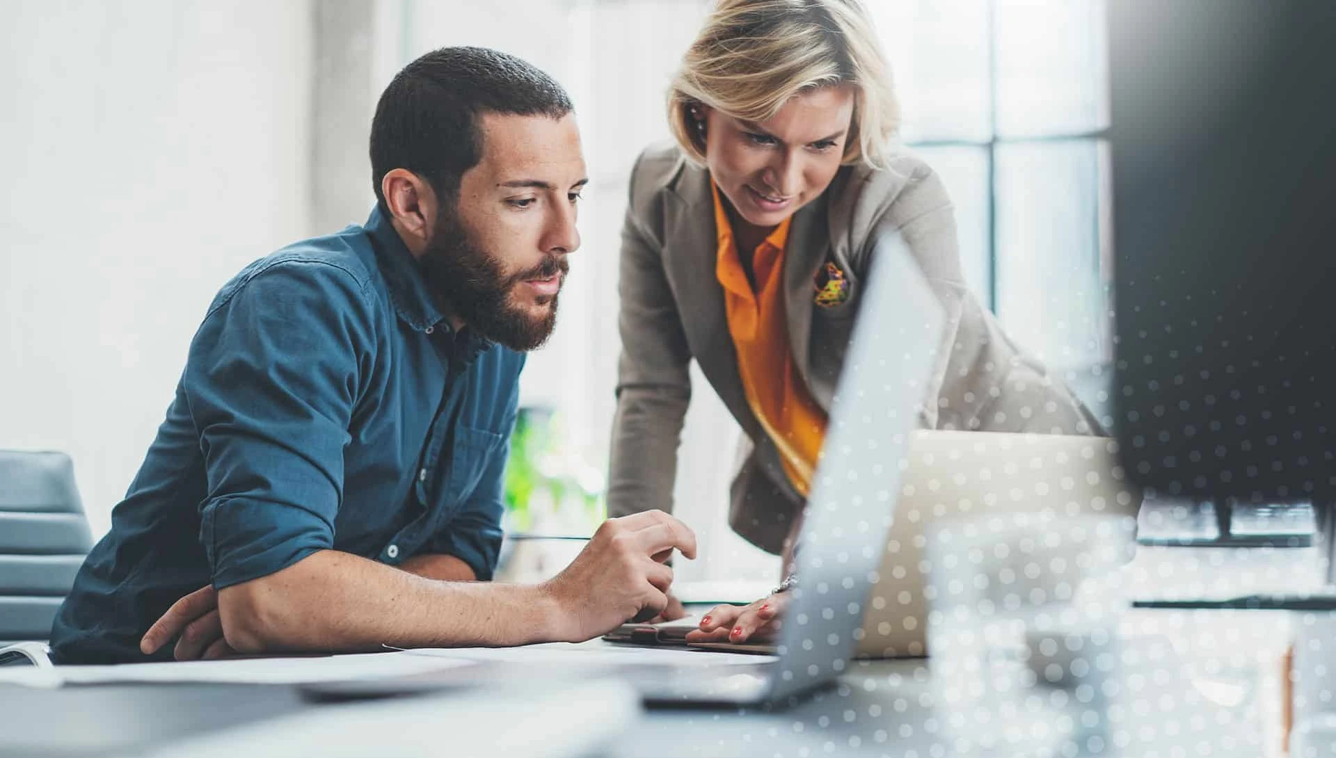 Two colleagues reviewing work together on a laptop
