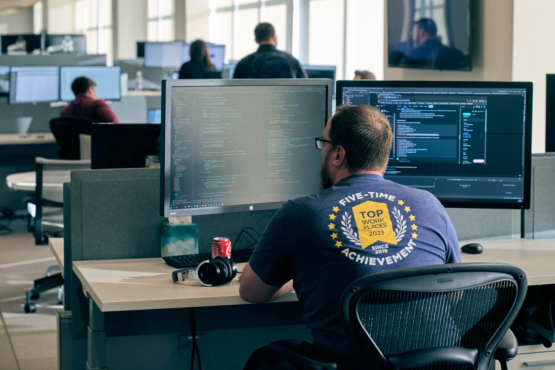An Unlimited Systems engineer in a Five-Time Top Workplaces shirt writing code at the Cincinnati headquarters
