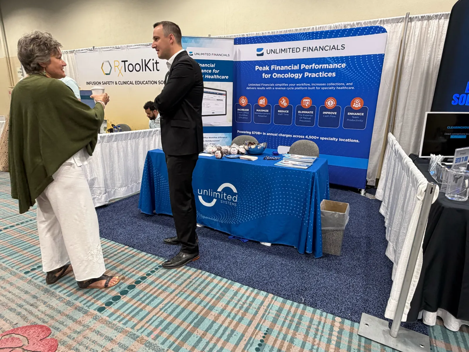 An Unlimited Systems team member talking with an attendee at the Unlimited Financials oncology RCM software booth