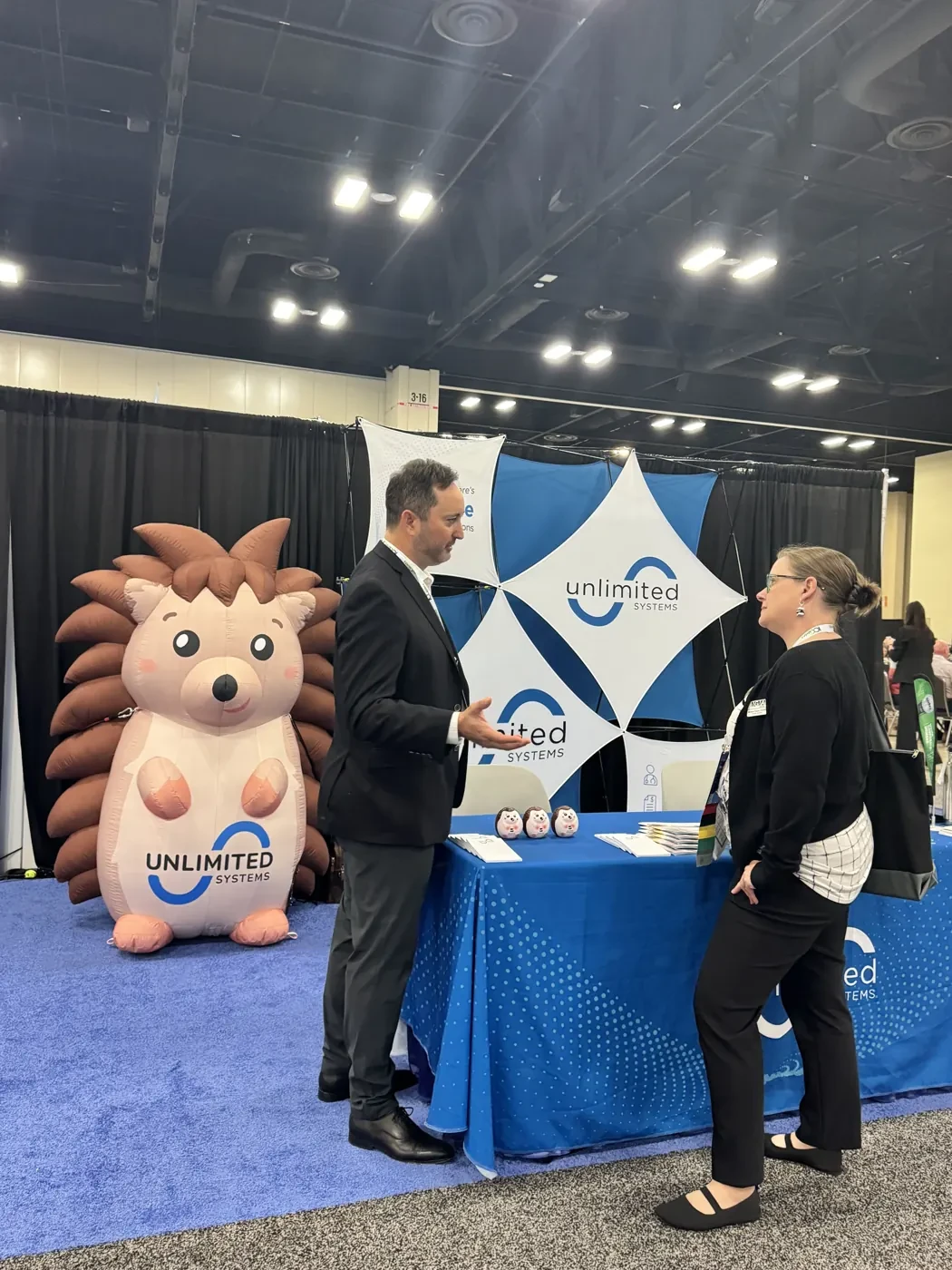 An Unlimited Systems team member discussing RCM software with an attendee at the MGMA 2026 conference booth
