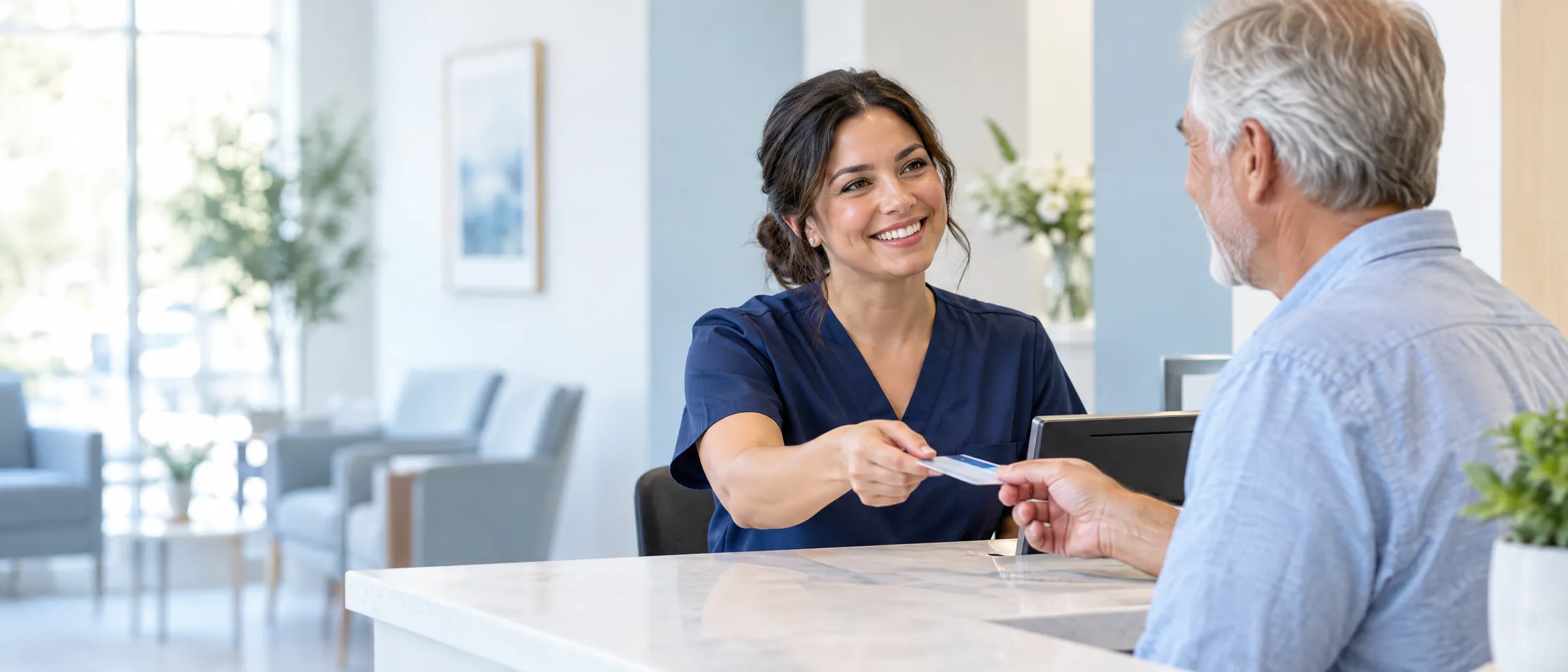 Front desk coordinator handing an insurance card back to a patient at check-in