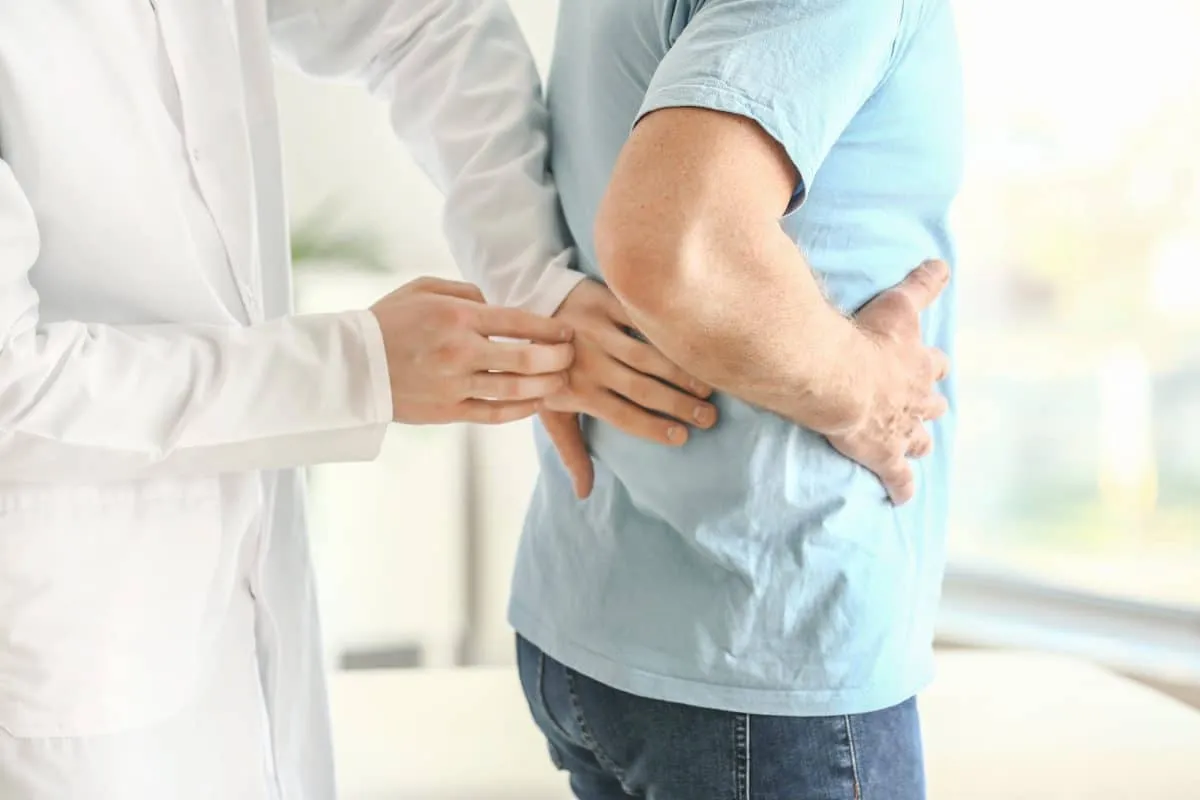Physician examining a patient holding his side for abdominal pain
