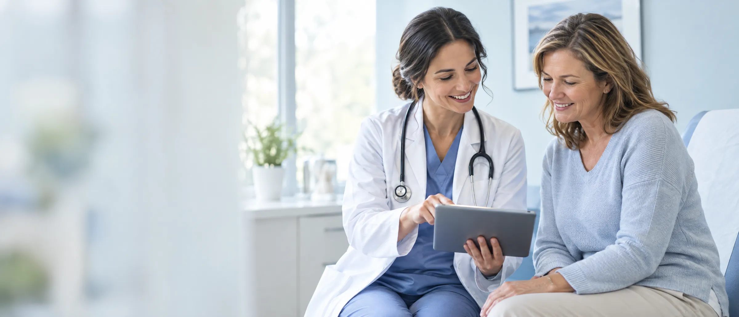 Physician showing a patient something on a tablet in a bright exam room