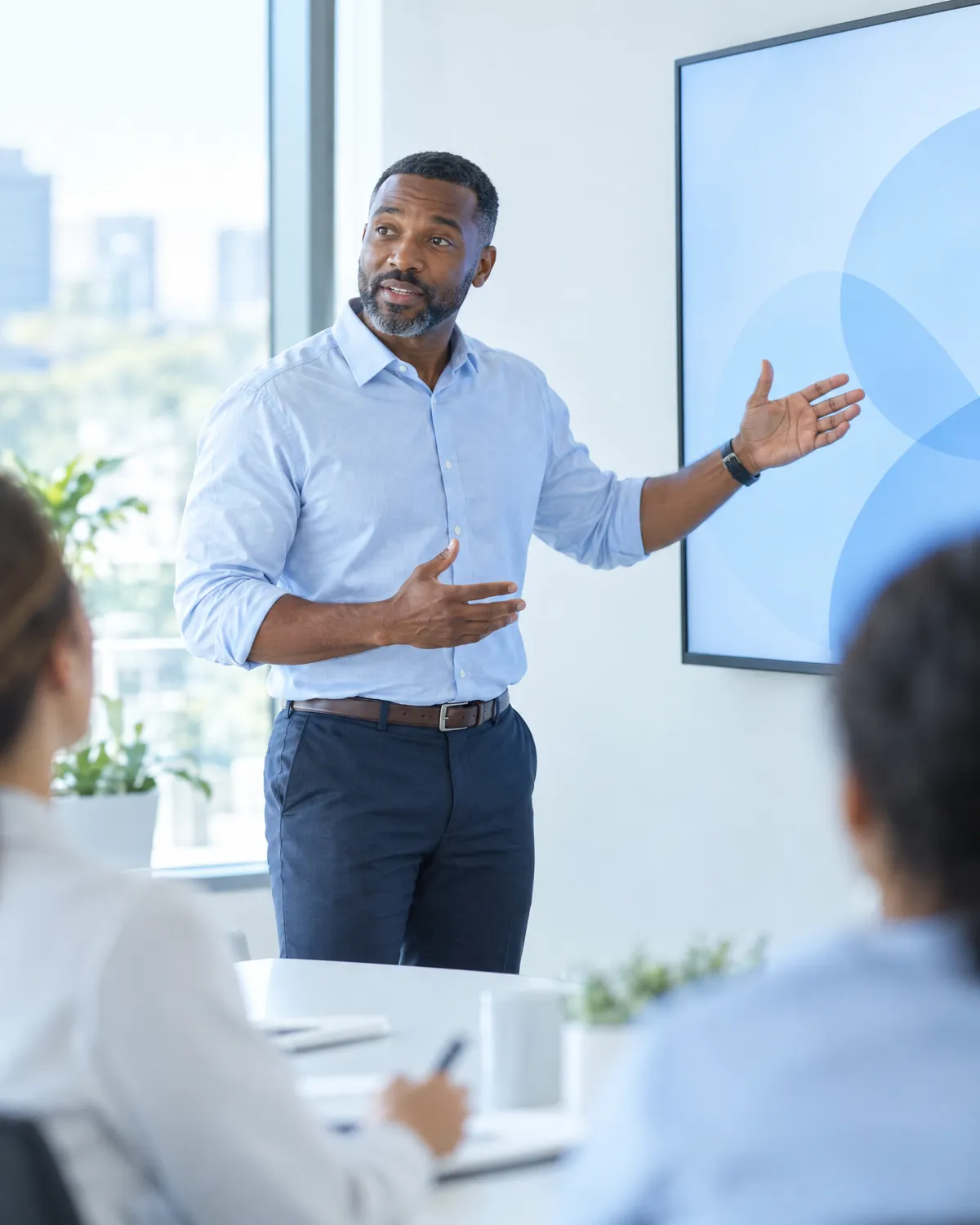 Revenue cycle director presenting to his team beside a wall display