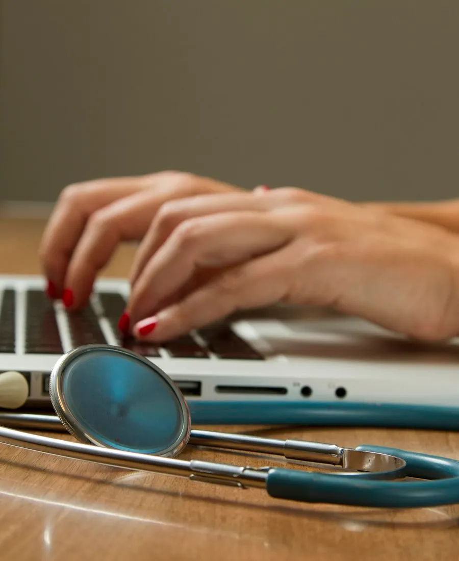 Clinic team member working claims at a laptop