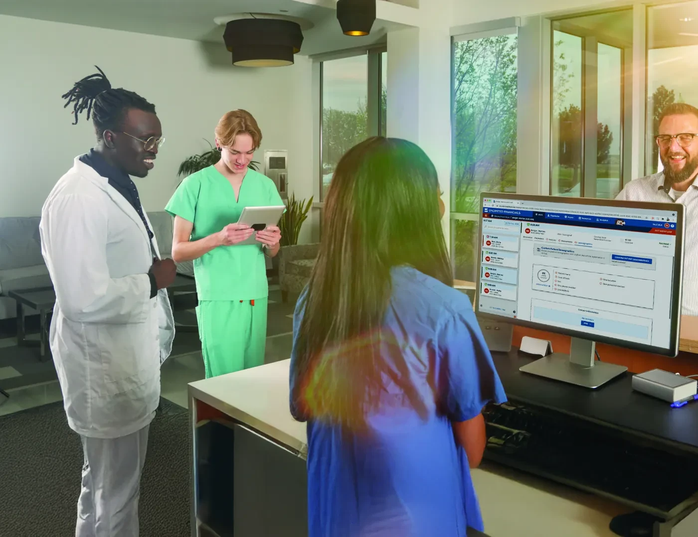Specialty practice management software in use: clinic staff at a front-desk workstation running Unlimited Financials